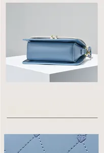 Close-up of heart embroidery texture and pearl zipper detail on light blue crossbody bag
