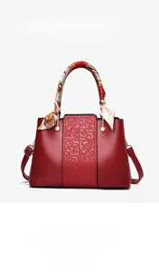 Close-up of elegant red bridal handbag with embossed leather texture and silk scarf handle