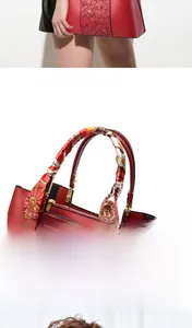 Detail einer roten Lederhandtasche mit feiner Blumenstickerei und einem Seidenschal am Griff