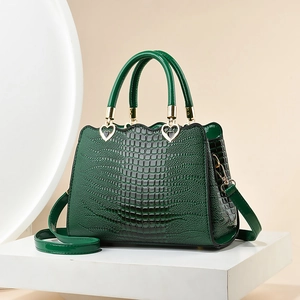 Sac à main vert foncé à motif crocodile avec des détails métalliques dorés en forme de cœur
