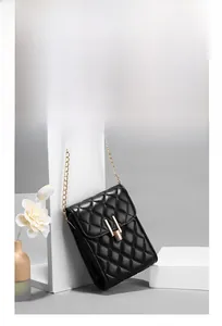 Detail of rhombic quilted phone bag featuring gold chain strap and metal lock closure