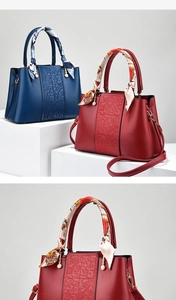 Detail of red wedding tote with embossed scroll patterns and silk scarf handle accents