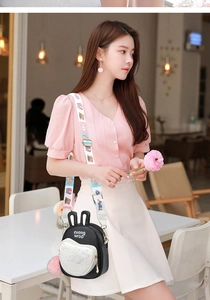 Detail of crossbody bag with white heart pocket, rabbit ears, and cartoon strap