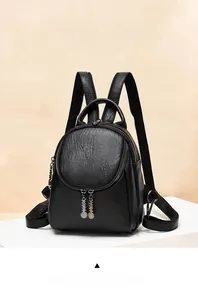Detail of black pebbled leather backpack showing multi-zipper layers and fishbone pulls