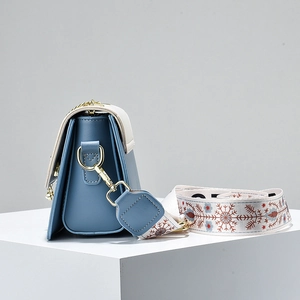 Blue and beige crossbody bag with wide snowflake embroidered strap on display