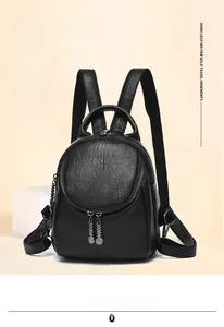 Detail of black pebbled leather backpack with dual zippers and decorative metal pendant