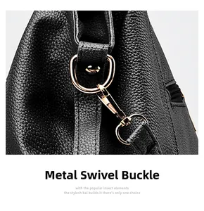 Close-up of golden metal swivel clasp and textured black litchi leather on handbag
