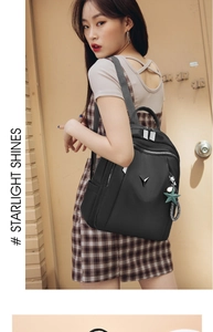 Detail of black nylon backpack with metal V logo and star pendant on female model