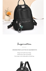 Detail of black backpack showing silver star charm and multi-pocket zipper layout