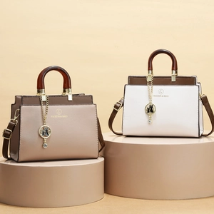 Dual-tone leather handbags with amber handles and cat charms on pedestal displays