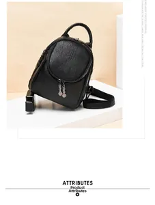 Detail of black pebbled leather mini backpack with metal zipper pulls on a white stand