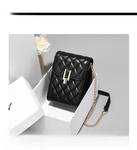 Detail of black quilted mobile phone bag with golden lock and chain strap in a gift box