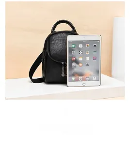 Mini black pebbled leather backpack size comparison with a tablet on a wooden background