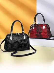 Detail view of crocodile pattern shell bags in black and gradient red with top handles
