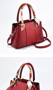 Detail of red bridal handbag featuring cloud-pattern embossing and a silk scarf handle