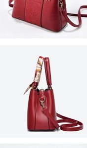 Detail of red bridal handbag with embossed scroll patterns and silk scarf handle decor