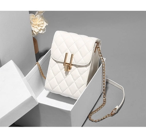 Close-up of white quilted mini bag with golden metal lock and elegant chain strap detail