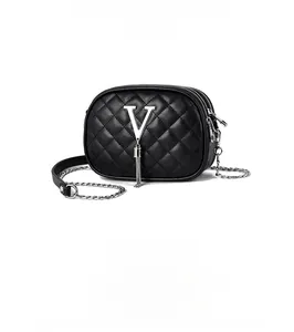 Close-up of black quilted crossbody bag with metal V logo, fringe, and triple zippers