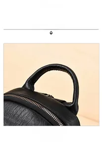 Close-up of litchi grain leather handle and metal zipper on black travel backpack