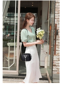 Fashionable black quilted crossbody bag with silver V-logo and tassels in a cafe setting