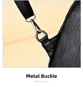 Detail of detachable metal lobster clasp and D-ring on black textured leather bag