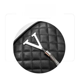 Detailed close-up of black quilted leather with silver V-shaped hardware and fringe tassels