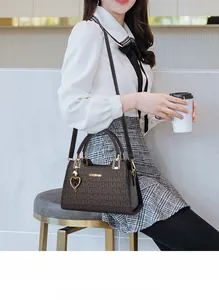 Detail showing the brown letter printed tote bag with a heart-shaped metal charm