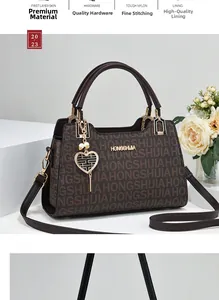 Detail of dark brown leather handbag featuring monogram pattern and gold heart pendant charm