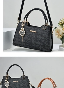 Detail of black satchel with HONGSHIJIA lettering and pearl heart charm accessory