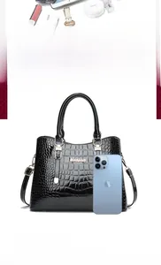 Detailed view of the large crocodile embossed tote bag next to a smartphone for scale