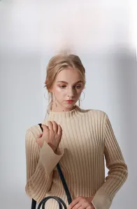 Gros plan d'un pull beige à col montant en maille côtelée avec un sac à main noir élégant