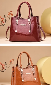 Close-up of glossy crocodile pattern handbags in wine red and tan with gold hardware
