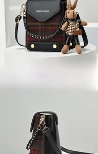 Close-up of retro crossbody bag with plaid fabric, gold rivets and a rabbit charm