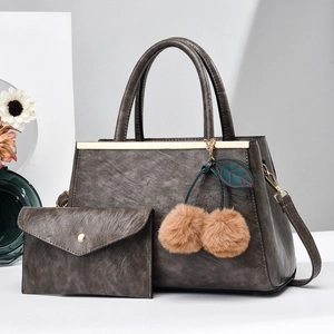 Detail of dark gray leather tote bag set with cherry pompom and matching envelope wallet