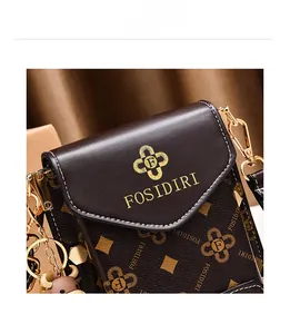 Détail du petit sac à bandoulière marron avec motifs trèfle et breloque tête de boeuf