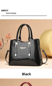 Close-up detail of glossy black crocodile embossed leather handbag with metal logo
