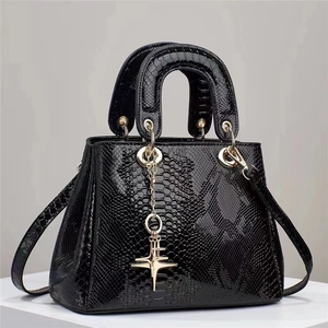 Close-up of black snakeskin texture with gold chain and star pendant on handbag