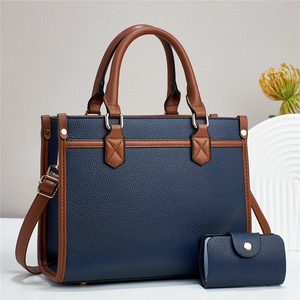 Detail of navy blue tote bag set with brown trim and matching card holder in pebbled leather