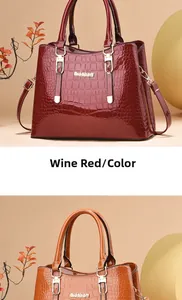 Detail view of burgundy and orange faux crocodile leather handbags with metal handles
