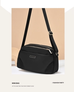Detail view of premium black nylon bag showing gold zippers and adjustable strap