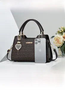 Brown monogram handbag size comparison with a smartphone and pearl heart charm detail