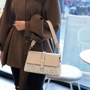 Detail of cream shoulder bag with monogram print and golden metal square lock buckle