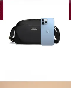 Size comparison of a black nylon crossbody bag with a smartphone showing compact capacity