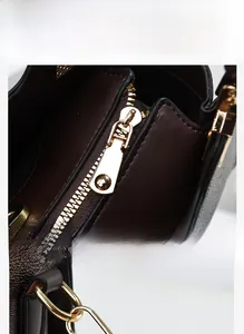 Close-up of golden metal zipper and side hardware hooks on dark brown leather bag