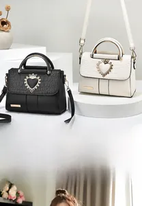 Detail of elegant embossed trapezoid handbags in black and cream with gold heart crowns