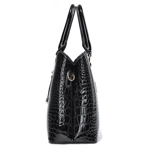 Glossy black crocodile pattern handbag with white contrast stitching in side view