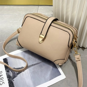 Dettaglio borsa a tracolla beige in pelle martellata con doppia zip e fibbia dorata