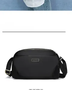Detail of waterproof nylon crossbody bag featuring metallic logo and adjustable strap