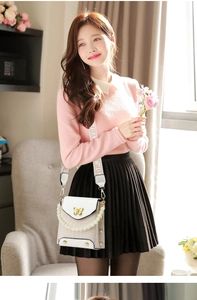 Detailed view of mini crossbody bag with gold butterfly accent and pearl handle