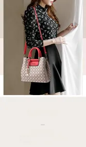 Detail of printed crossbody bag with red woven handles and logo pendant on floral background